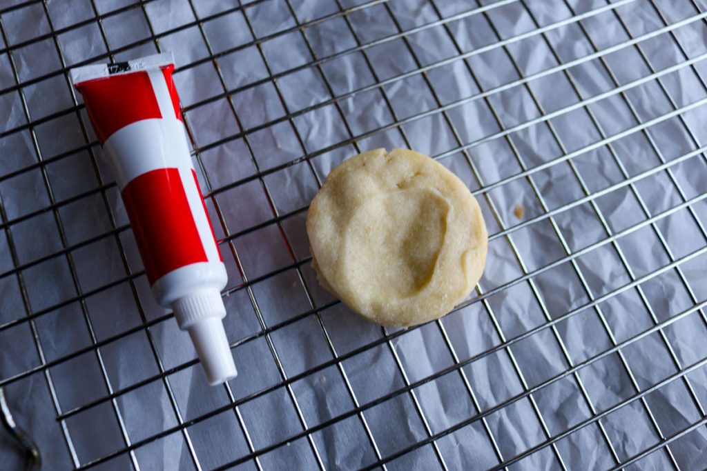 thumbprint cookie with red icing tube next to it