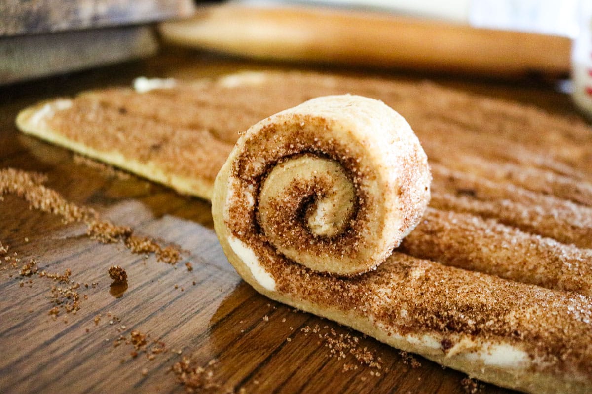 cinnamon roll dough strips being rolled up