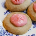 a small bite sized sourdough shortbread tea cookie with pink icing on a white and blue plate