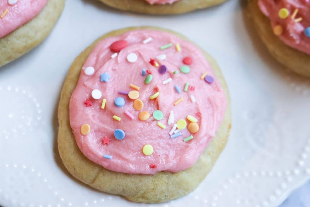pink iced sugar cookies with sprinkles on parchment