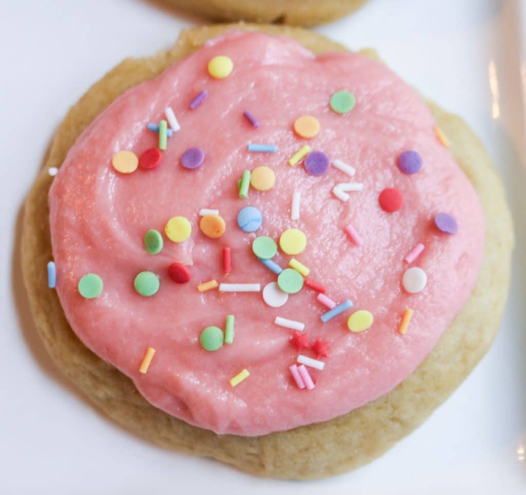pink iced sugar cookies with sprinkles on parchment