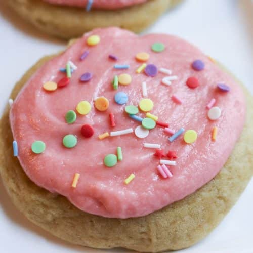 pink iced sugar cookies with sprinkles on parchment