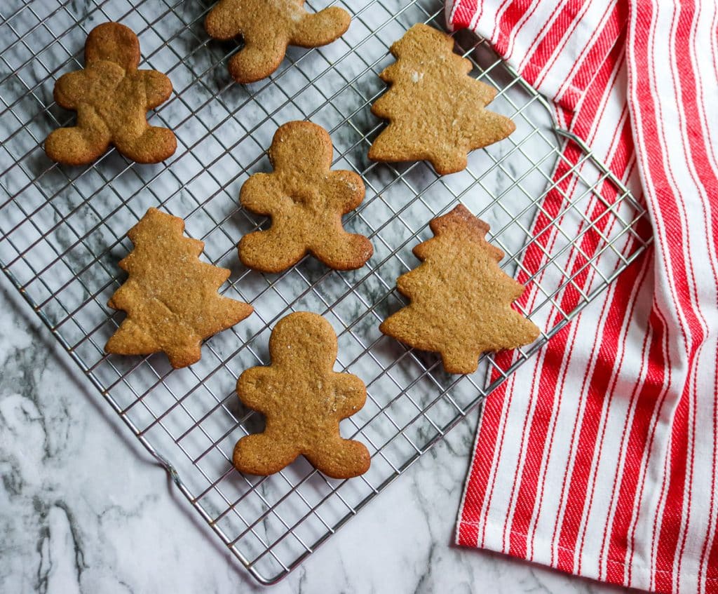 gingerbread cookies in the shape of men and trees on a baking sheet on a marble counter