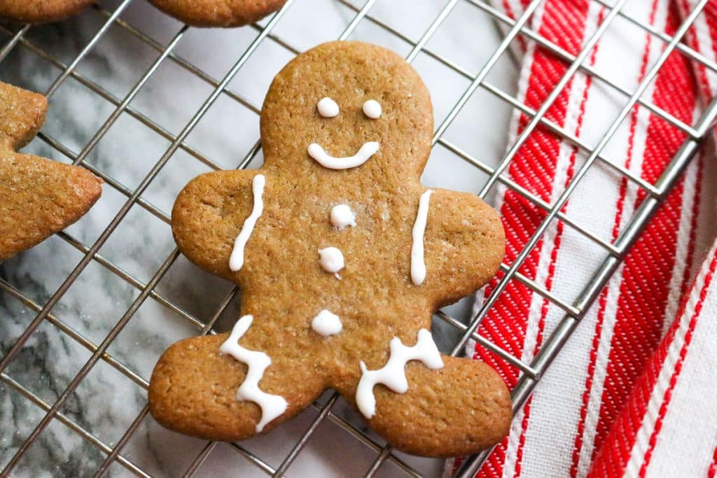 iced gingerbread man on a cooling rack on top of a marble counter with a red and white towel.