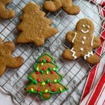 iced gingerbread cookies in the shape of men and trees on a baking sheet on a marble counter