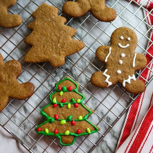 iced gingerbread cookies in the shape of men and trees on a baking sheet on a marble counter
