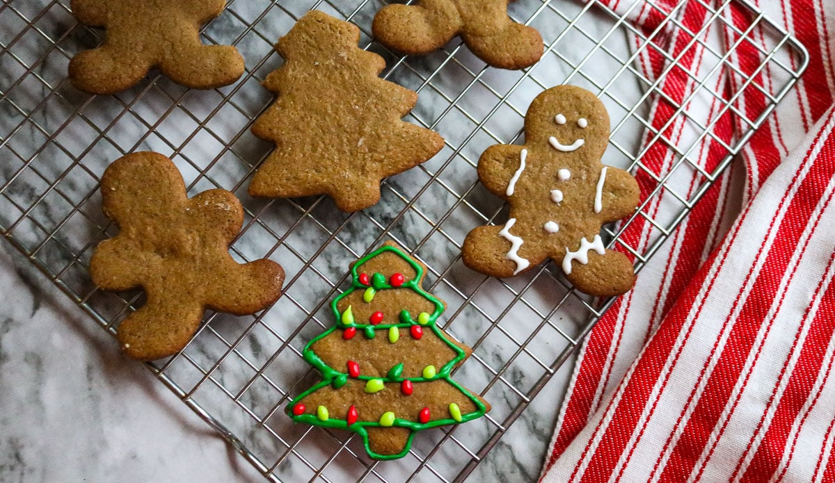 iced gingerbread cookies in the shape of men and trees on a baking sheet on a marble counter