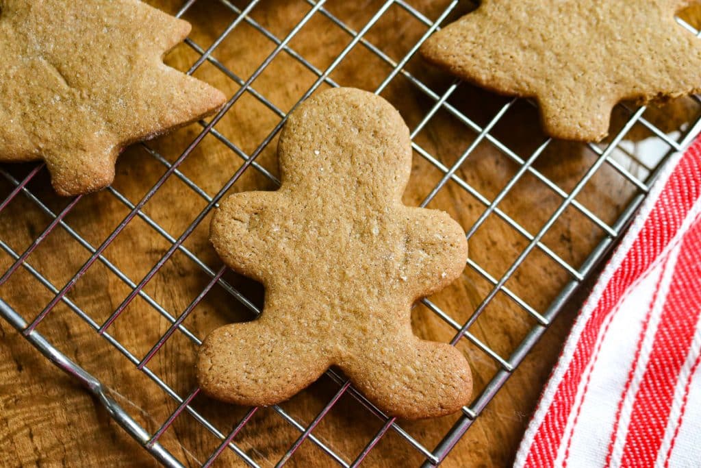 gingerbread cookies in the shape of men and trees on a baking sheet on a wooden counter