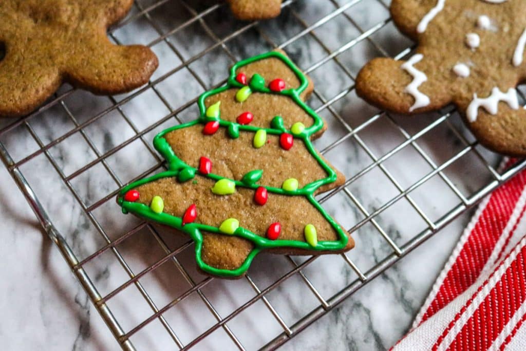 iced gingerbread cookies in the shape of men and trees on a baking sheet on a marble counter