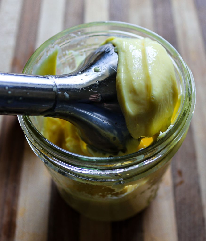 Immersion blender making homemade mayonnaise in a glass jar, showing thick, creamy mayo forming from simple ingredients.