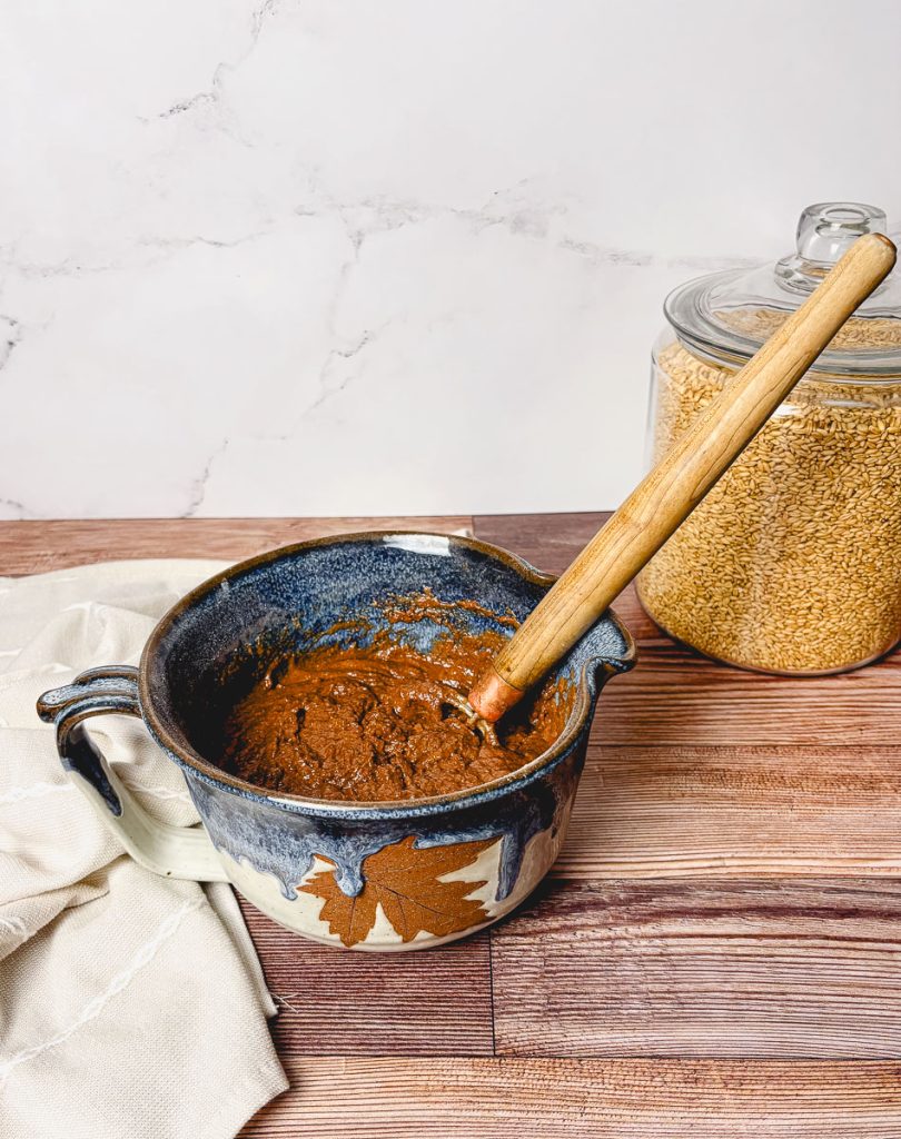 a blue and white pottery bowl full of double chocolate muffin batter with a danish whisk