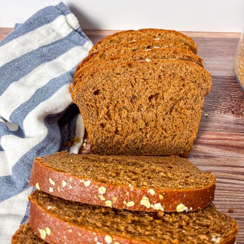 a loaf of brown bread sliced, with a close up of the interior texture on a blue and white tea towel
