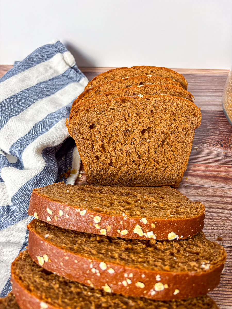 a loaf of brown bread sliced, with a close up of the interior texture on a blue and white tea towel